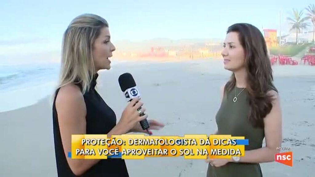 Repórter entrevista a dermatologista Dra. Rafaela Salvato na praia, em pauta da NSC TV sobre fotoproteção